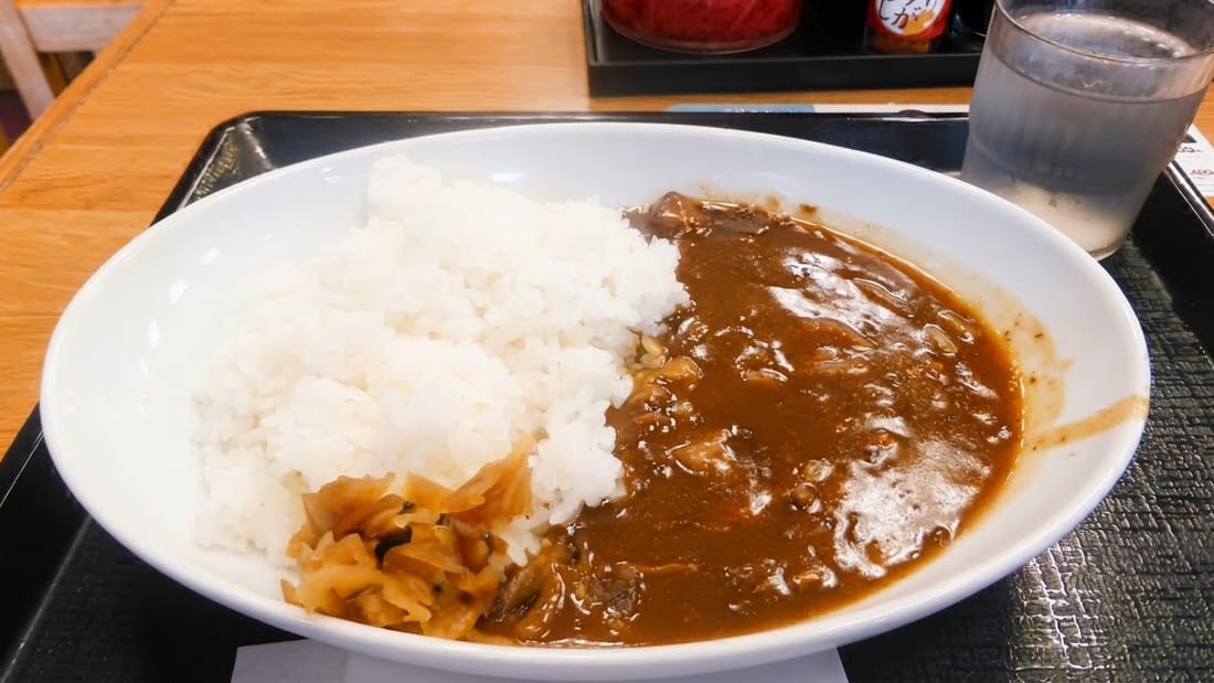 Chicken curry with rice on a canteen tray under dim indoor light — after