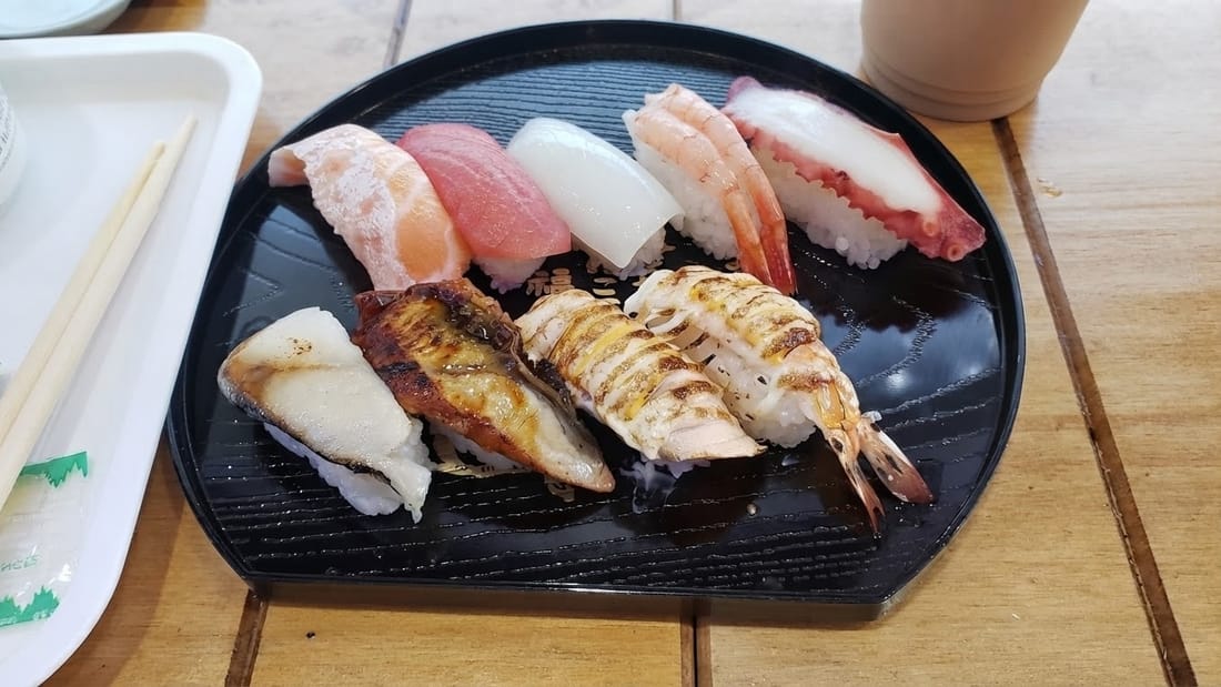 A plate of nigiri sushi on a wooden counter, slightly dull colours — after