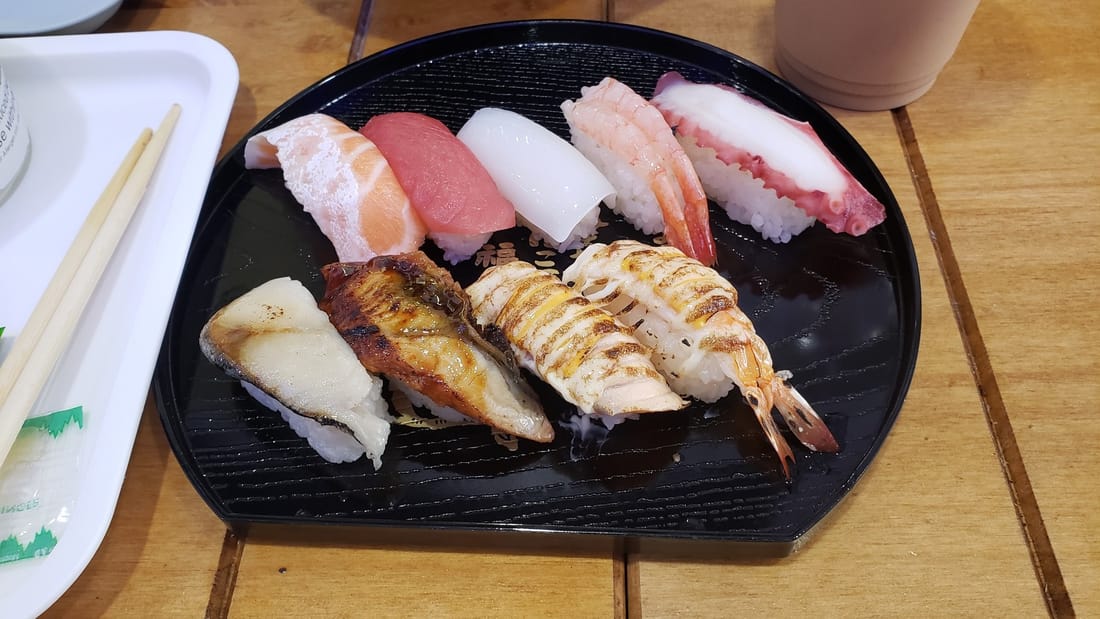 A plate of nigiri sushi on a wooden counter, slightly dull colours — before