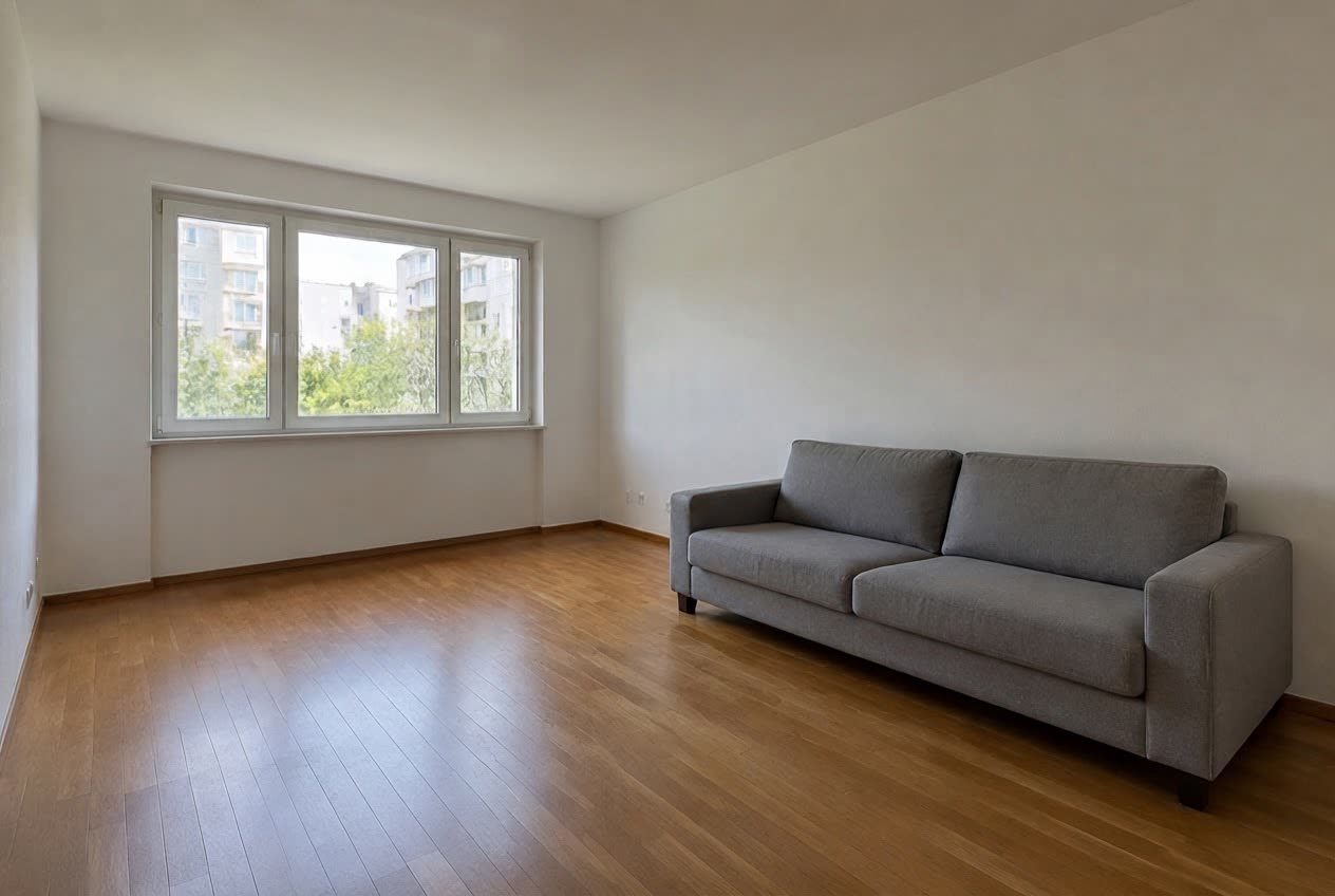 A bright living room with a grey sofa and a radiator under the window — after