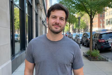 A man in a grey T-shirt on a city street